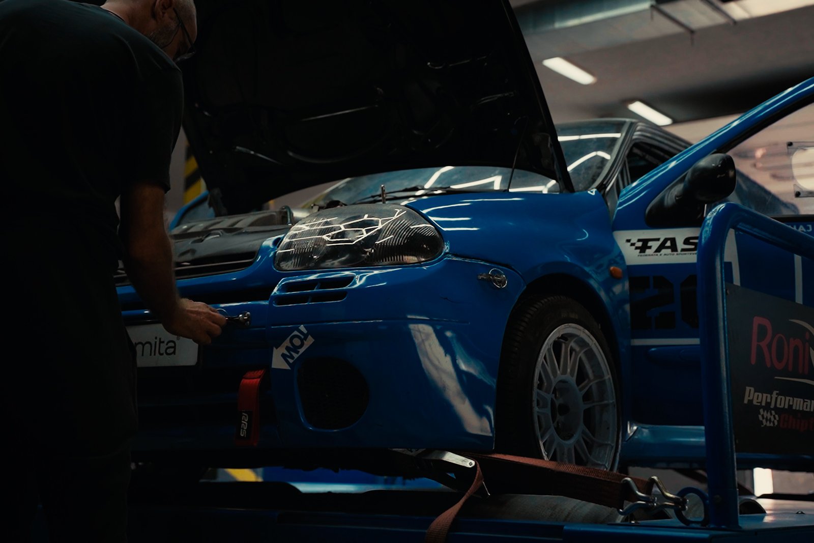 Color-graded still of a blue performance car in the Roni Performance workshop.